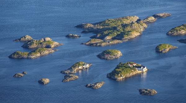 Small rocky islands with individual houses in the sea, archipelago islands, near Henningsvær,