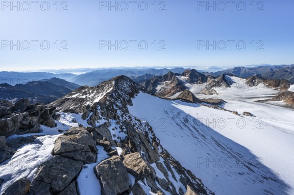Narrow rocky ridge at the Wilder Freiger summit, picturesque high mountain landscape with snow,