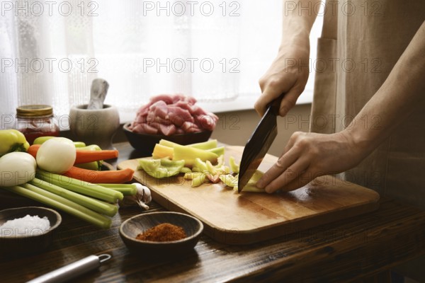 Hands skillfully cut bell pepper on a wooden board in a bright kitchen. Fresh meat and various