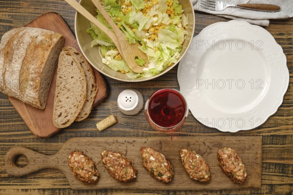 A hearty meal is prepared with freshly made meat patties, a vibrant salad with corn and greens, and