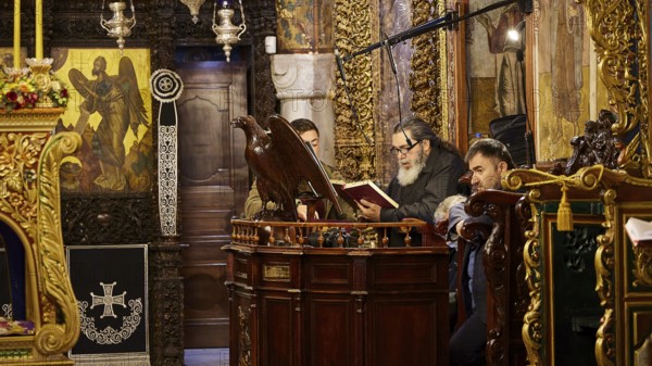 Men reading from religious books in a church decorated with icons, Holy Week, Bay of Panormitis,
