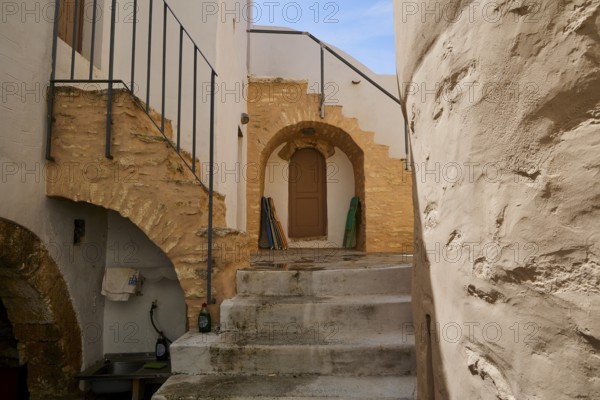 Historic courtyard with stairs, stone arches and wooden doors in the sunlight, Monastery, Moni