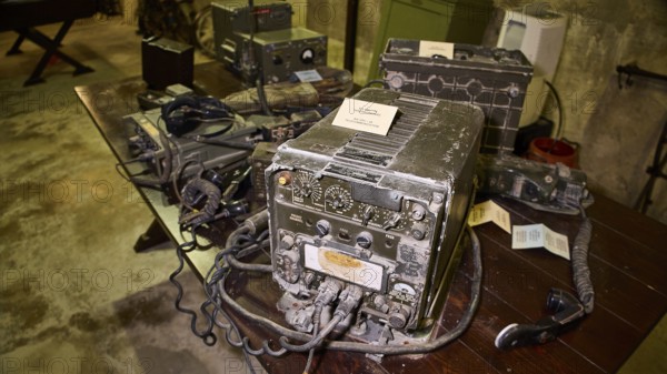 A pile of antique radios on a dark wooden table in a bunker, War Museum, Military Museum, Tunnel