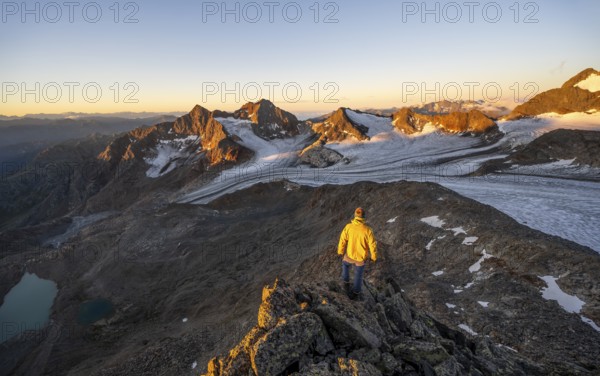 Mountaineers in front of a picturesque high mountain landscape at sunrise with alpenglow, blue