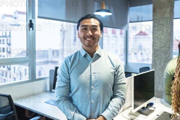 Portrait of a smiling asian businessman standing in a bright, modern office, conveying confidence