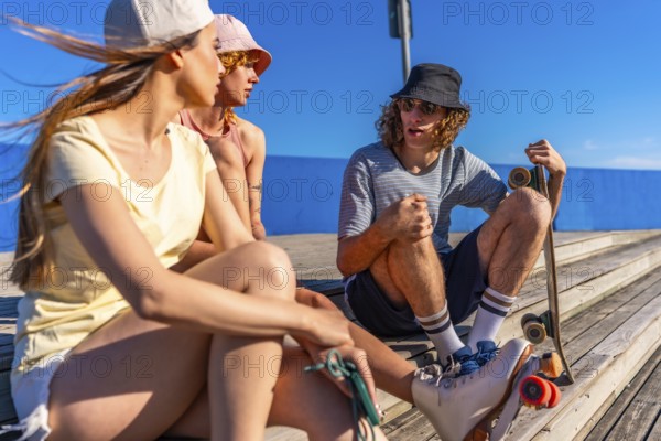 Group of friends chatting and having fun on a wooden pier, enjoying summer and seaside lifestyle