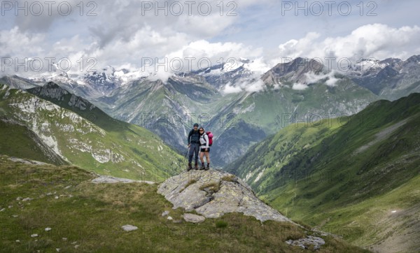 Two friends, mountaineers on a rock at the Mittagskögele, view of mountain peaks of the Venediger