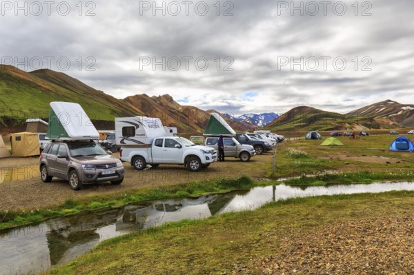Off-road vehicle with roof tent, camping site in Landmannalaugar, Icelandic highlands, rain clouds,