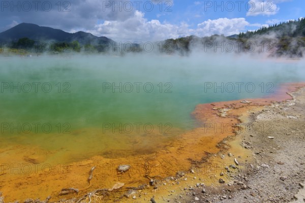 A steaming hot spring with an orange-coloured rock edge, Champagne Pool thermal lake, Wai-O-Tapu