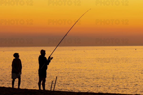 A man fishing just in front of sunrise on the Costa Rei, a coastline of the Italian island of