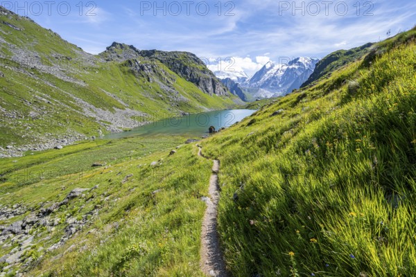 Hiking trail in a picturesque mountain landscape, view of the Lac du Louvie mountain lake and