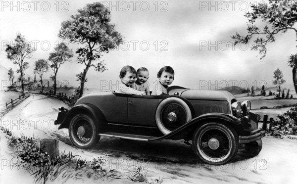 Three babies in a car, 1920s, Three children in a vintage car on a rural road, surrounded by trees,