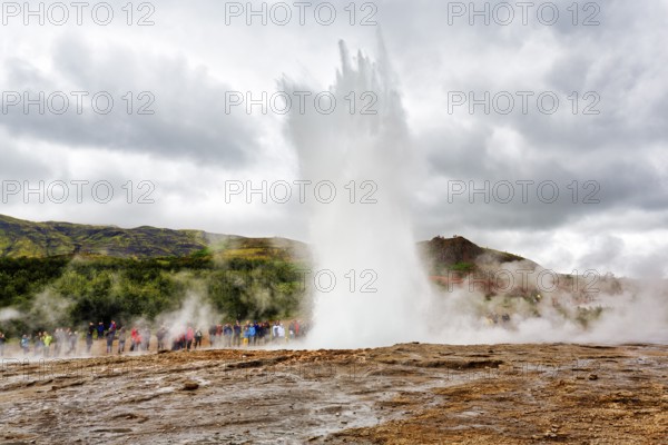 Active Strokkur, tourists observe eruption, high temperature area Haukadalur, tourist attraction at