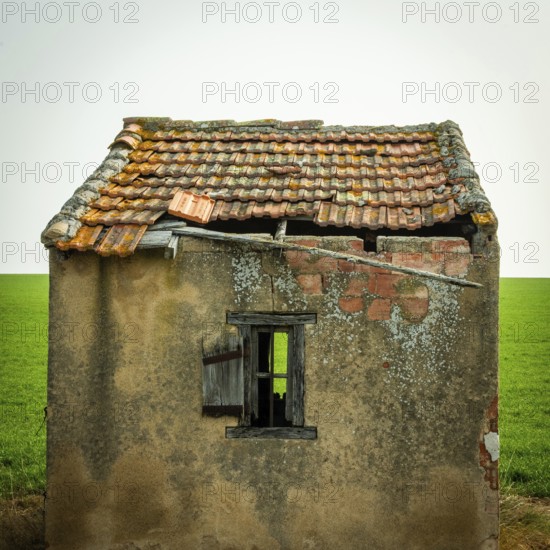 A small, abandoned structure shows signs of wear, with a crumbling roof and exposed brick. The