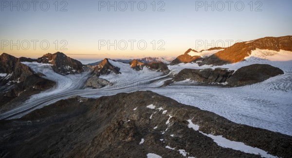 Picturesque high mountain landscape at sunrise with alpenglow, glacier and rocky mountain peaks in