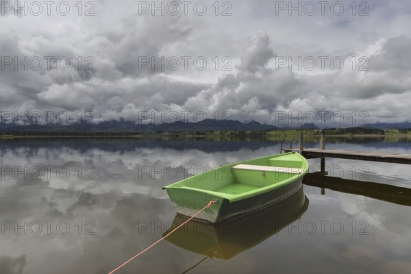 Storm clouds at sunset, a green rowing boat lashed to the wooden jetty, Hopfensee, Hopfen am See,