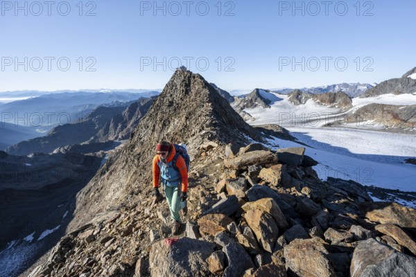 Mountaineer on a rocky ridge, ascent to the Wilder Freiger, summit of the Becher with Becherhaus