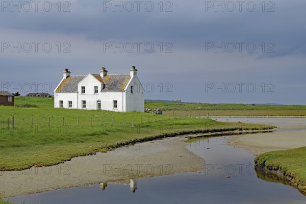 Lonely white house in a green field under a cloudy sky, Isle of Harris, Hebrides, Scotland, United