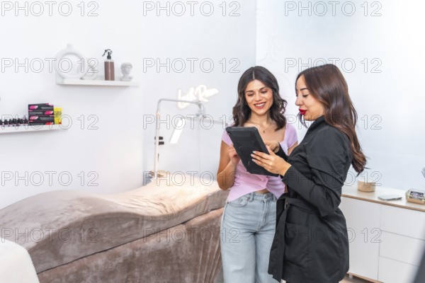 Beautician and customer discussing treatment options while using a digital tablet in a modern,