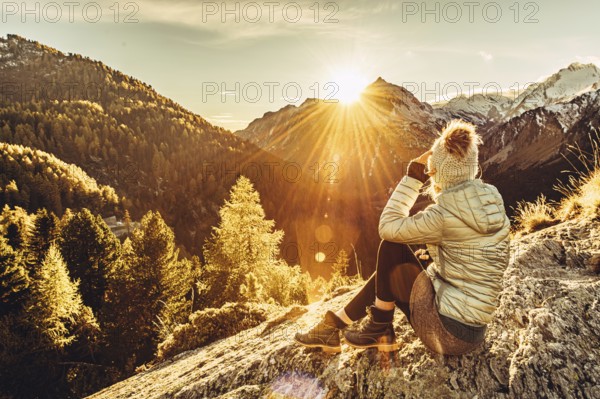 Woman sitting thoughtfully at a feslen at autumn atmosphere during sunset in the Swiss Alps in the