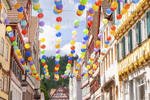 Colourful balloons decorate a narrow street in a picturesque old town under a sunny sky, Calw,