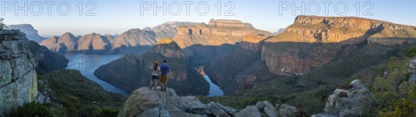 Two hikers enjoying the panorama, sunset at Blyde River Canyon with Three Rondawels peak, view of