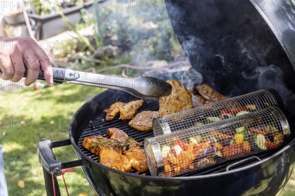 Barbecue in the garden. Meat and vegetables, vegetarian and vegan, are served on the kettle grill.