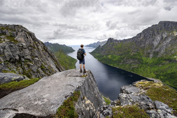 View of Øyfjorden fjord and mountains, view from Barden mountain, young man standing on a cliff,