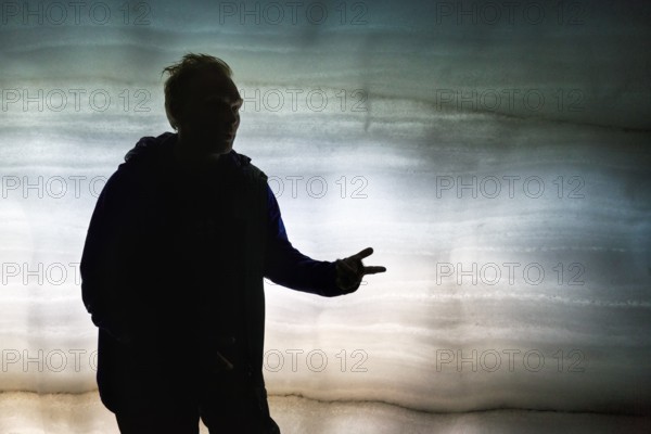 Guided tour through ice tunnel, glacier cave, tourist guide explains, backlight, glacier tour,
