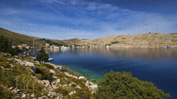 Coast with blue water and hilly landscape under a clear sky, Bay of Emporio, Emporio, Symi,