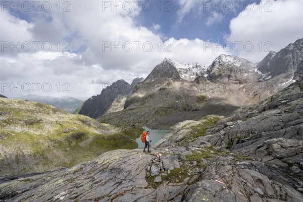 Mountaineer on a rocky hiking trail, view of the turquoise-blue mountain lake Großer Gradensee,