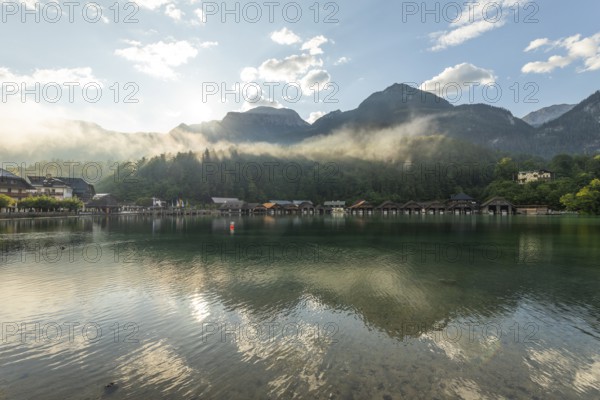 Mystical morning at Königssee in Schönau with boathouses. Sunrise and beautiful wafts of mist over