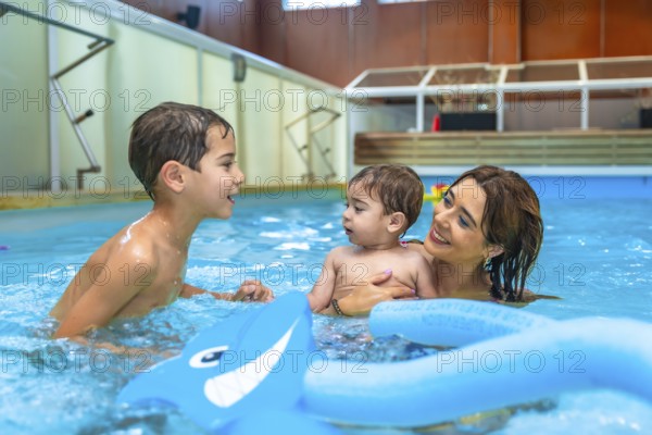 Mother and children enjoying time together, playing with inflatable toys in a swimming pool,