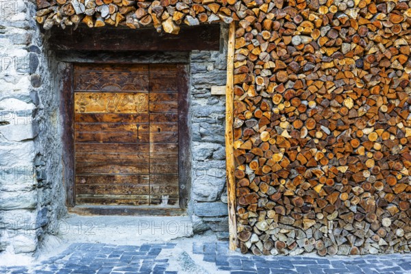 Entrance to a wine cellar framed by firewood logs, historic village centre, Grimentz, Val
