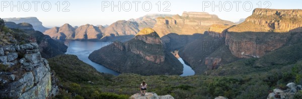 Hiker enjoying panorama, sunset at Blyde River Canyon with Three Rondawels peak, view of canyon