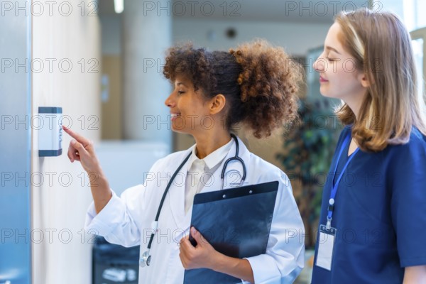 Female doctor entering security pin code on keypad access control, next to a nurse, in a hospital