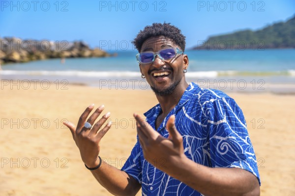 Young man enjoying summer vacation on a tropical beach, smiling widely and gesturing joyfully while