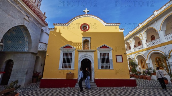 Yellow baroque-style church with cross and floor pattern in the courtyard, Holy Week, Panormitis