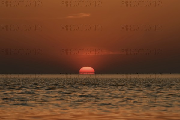When the red sun sinks into the sea... Cuxhaven, North Sea, sunset in calm weather, glowing red