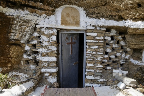 A rustic stone door with a cross symbolises a cave entrance that carries religious significance,