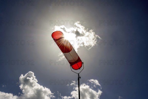 A colorful windsock hangs from a tall pole, clearly indicating wind direction. The bright sky is