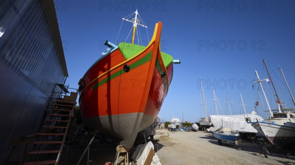 Frontal view of a ship's bow in orange and green on a shipyard site, Diakofti boatyard, new