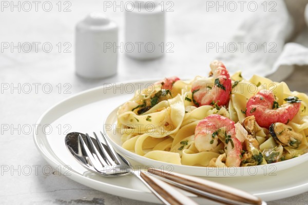 A plate of fettuccine allo Scoglio features fresh pasta topped with shrimp, mussels, and herbs,