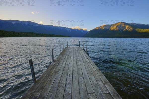 Wooden walkway stretches across the lake with mountains at sunrise, summer, Lake Rotoiti, Saint