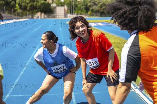 Runners stretching their legs on a vibrant blue track, recovering after a race, embodying teamwork