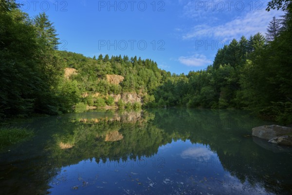 Tranquil lake in the middle of a forest with a clear water surface that reflects the sky,