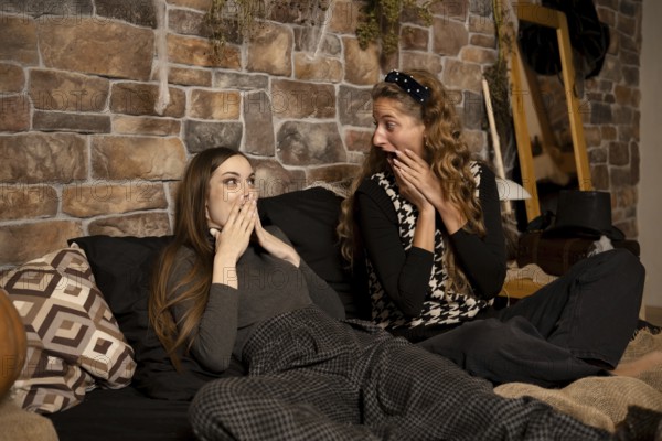 Two friends express surprise and excitement while lounging on a comfortable bed in a warmly