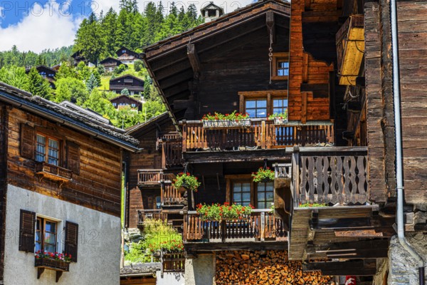 Old wooden houses in log construction, decorated with flowers, historic village centre, Grimentz,