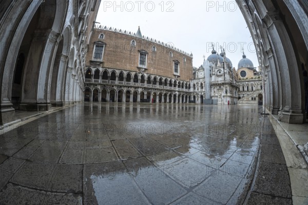 The doge's palace courtyard glistens with rainwater on a cloudy day in venice, italy, showcasing