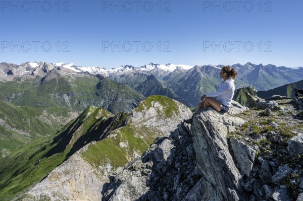 Mountaineer sitting on a rock in front of a mountain panorama with Großvenediger, mountain